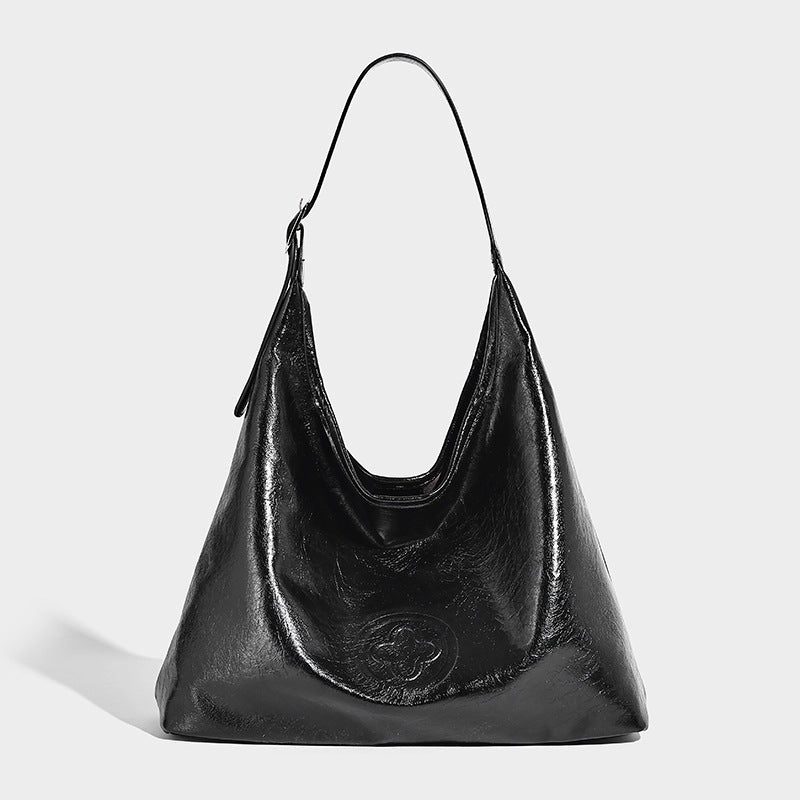 Glossy slouchy hobo shoulder bag with adjustable strap and embossed floral emblem, detail view 6
