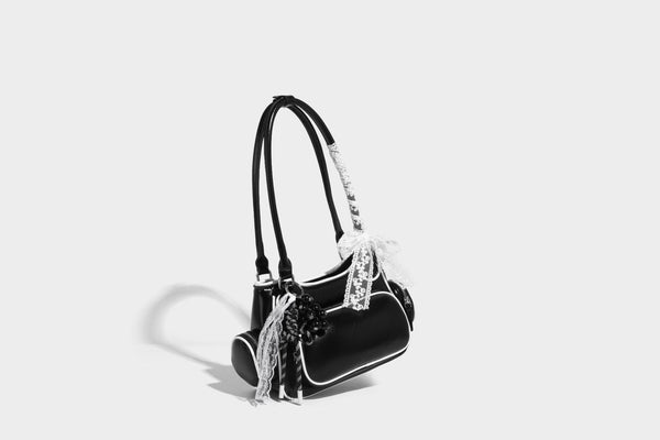 Kleine, formstabile Schultertasche mit glänzender Oberfläche, weißem Paspelbesatz, Spitzenschleife und rotem Perlenanhänger, Reißverschluss-Seitentaschen und silberfarbenem