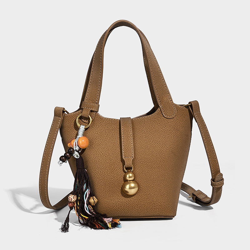 Kleine Beuteltasche mit genarbter, matter Oberfläche, antikgoldfarbenen Ringbeschlägen, Perlen- und Quastenanhänger, kurzen Henkeln und