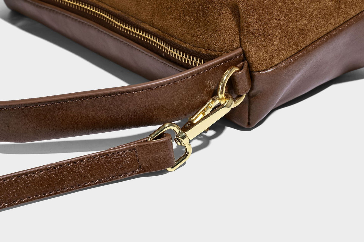 Kompakte Boston-Schultertasche in warmem Braun in Wildlederoptik mit glattem dunkelbraunem Besatz, übergroßen goldfarbenen Ringelementen und Reißverschluss oben