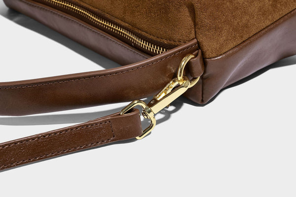 Kompakte Boston-Schultertasche in warmem Braun in Wildlederoptik mit glattem dunkelbraunem Besatz, übergroßen goldfarbenen Ringelementen und Reißverschluss oben