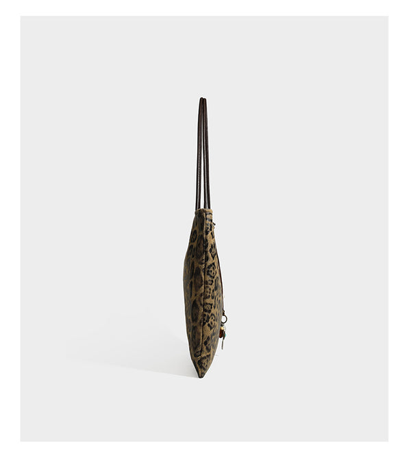 Large leopard print shoulder tote bag in tan and brown with slim dark straps and dangling beaded charm hardware, detail view