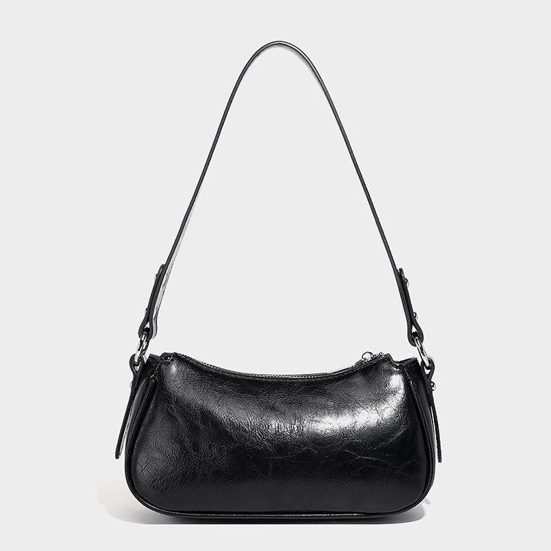 Compact moto-inspired shoulder bag with crisscross grommet strap detail, glossy textured finish, and adjustable crossbody