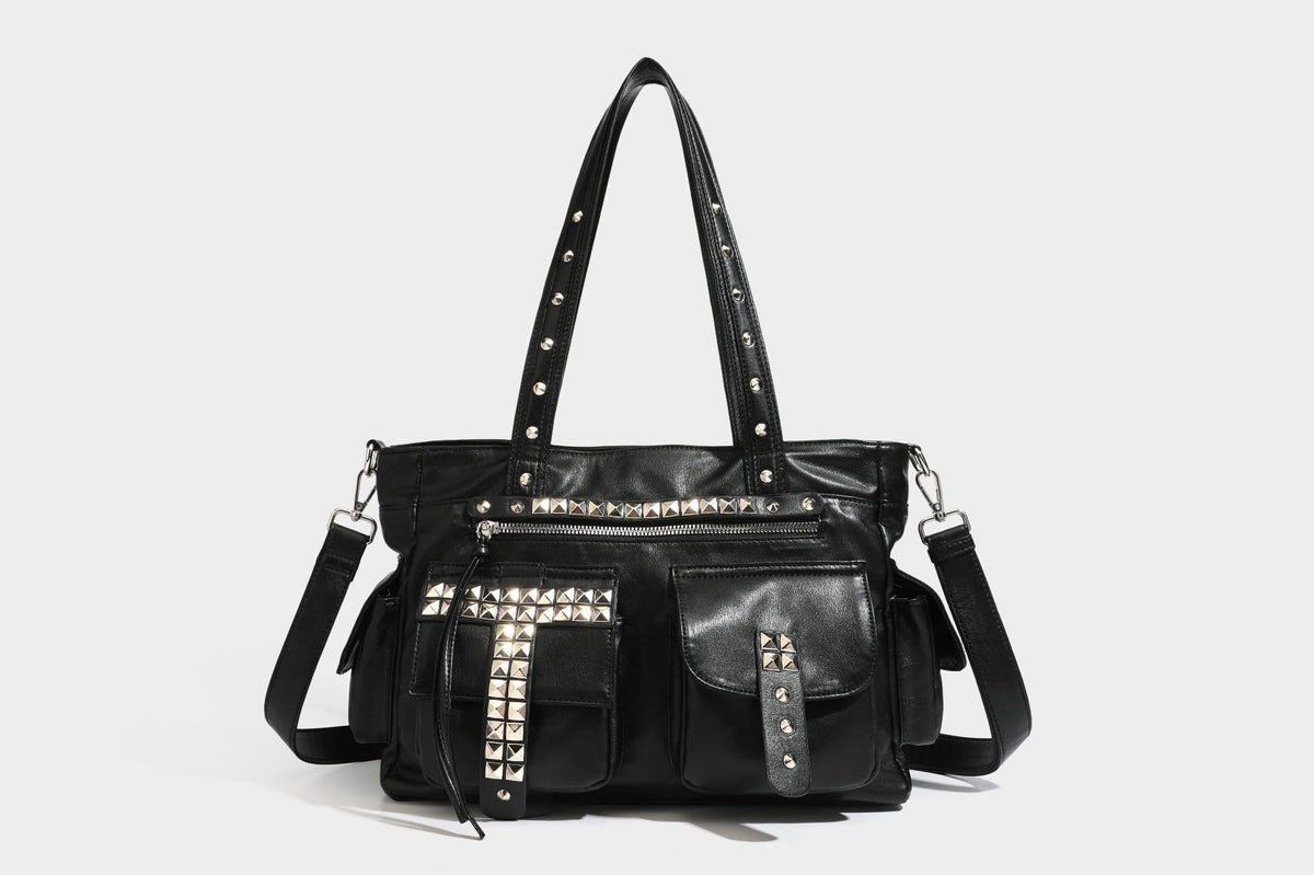 Black leather-look tote bag with silver pyramid studs on handles and front panel, multiple flap and zip exterior pockets