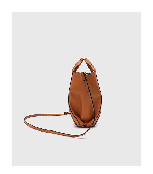 Structured open-top tote bag in tan brown pebbled leather-look finish with vertical seam accents, black edge piping, curved