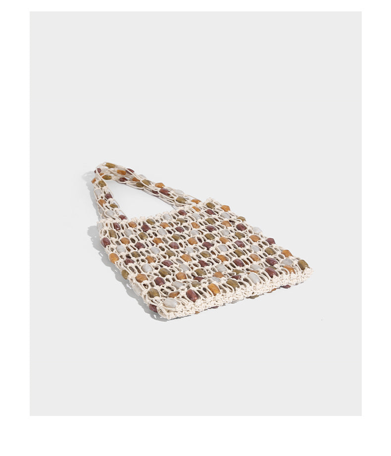 Cream macramé open-weave tote bag with multicolor amber olive and translucent bead accents and woven shoulder straps, detail