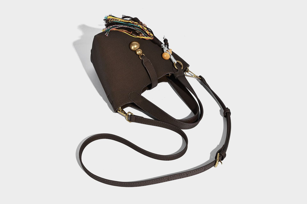 Kleine matte Beuteltasche mit genarbter Oberfläche, antikgoldfarbenen Ringbeschlägen, Perlen- und Quastenanhänger, kurzen Tragegriffen oben und