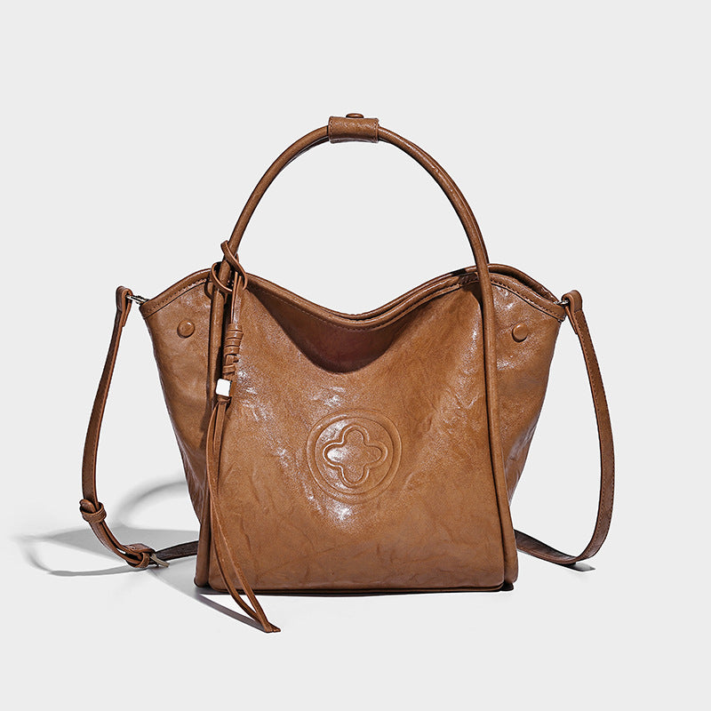 Glänzende Tote-Bag in geknautschter Lederoptik mit geprägtem Rundemblem, Quastenverschluss, zwei Tragegriffen und abnehmbarem