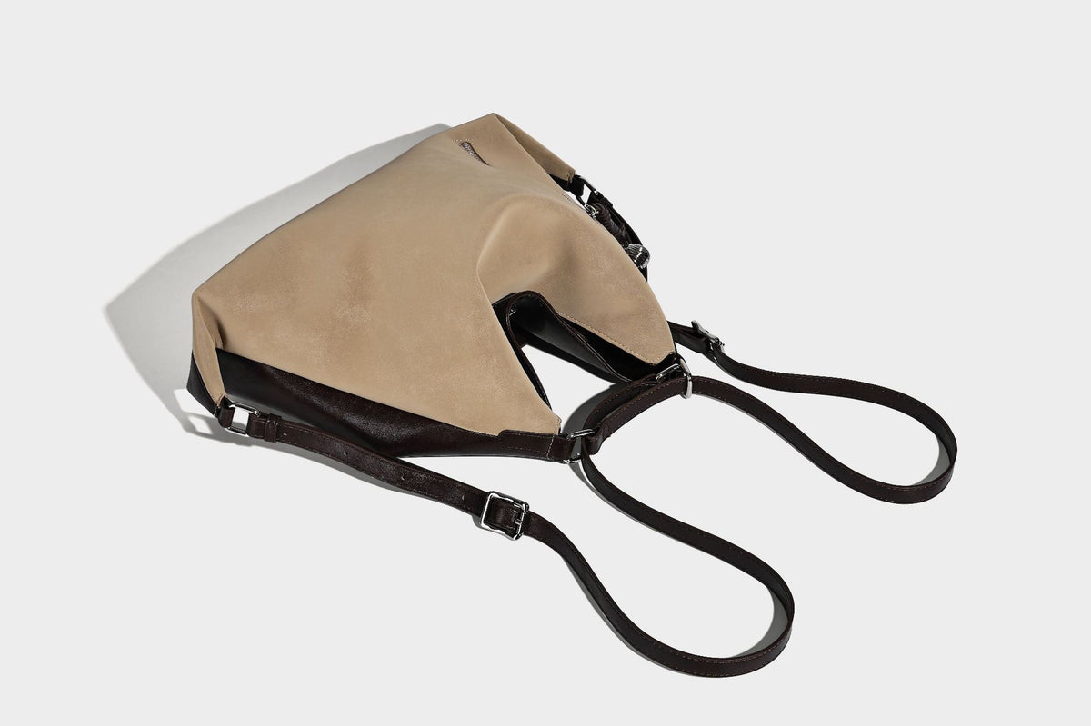 Slouchy hobo tote bag with matte leather-look finish, triangular silhouette, front zip pocket, and adjustable shoulder strap