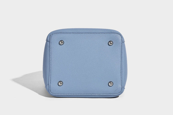 Small structured pebbled bucket tote bag with dual top handles, silver turn-lock front pocket, and detachable shoulder strap