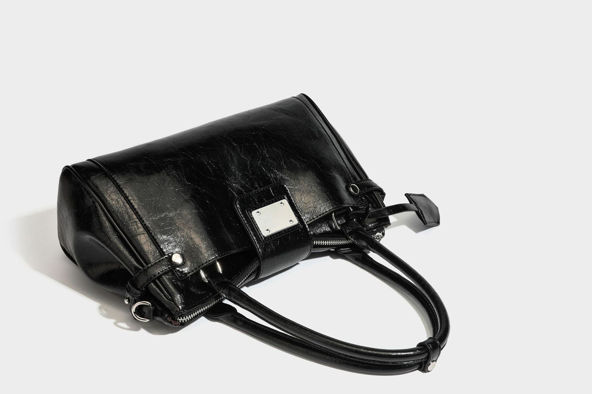 Structured glossy crinkled leather-look satchel with double top handles, front metal-plaque tab, silver-tone hardware, and