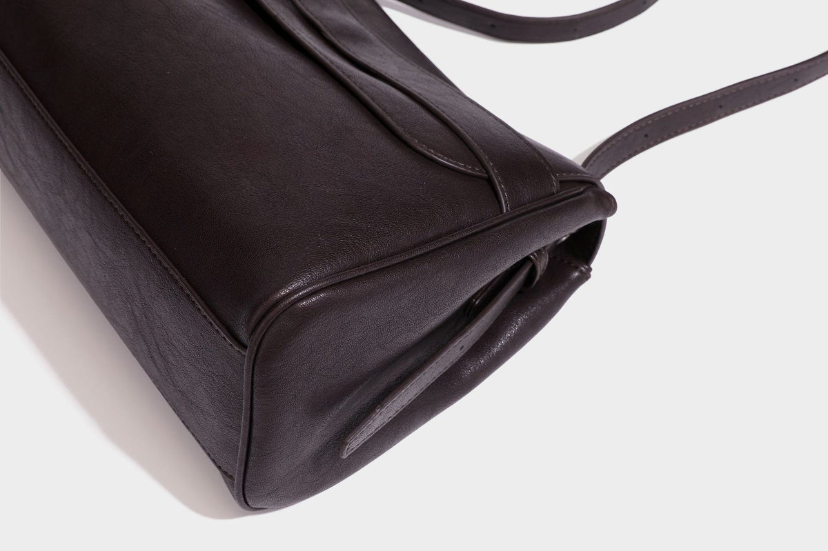 Formstabile rechteckige Schultertasche in Dunkelbraun mit Lederoptik, Überschlag und mehrlagigem Frontdetail sowie langem verstellbarem Riemen, Detail