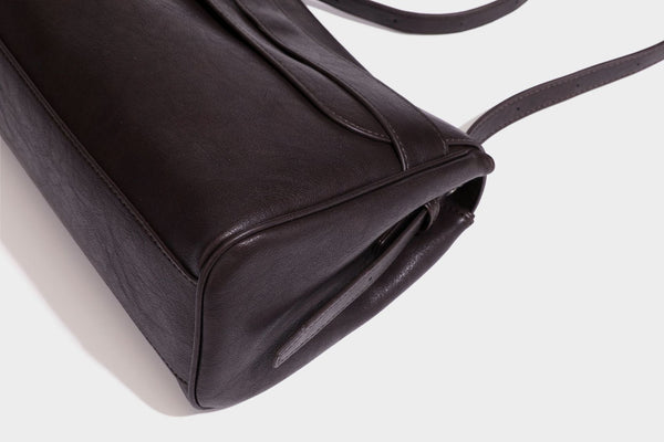 Formstabile rechteckige Schultertasche in Dunkelbraun mit Lederoptik, Überschlag und mehrlagigem Frontdetail sowie langem verstellbarem Riemen, Detail