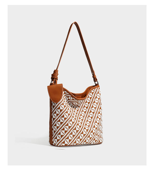 Geflochtene Schultertasche mit geometrischem Ethno-Muster, Besatz in dunkelbrauner Lederoptik, langem verstellbarem Träger und kleinem hängendem Reißverschluss