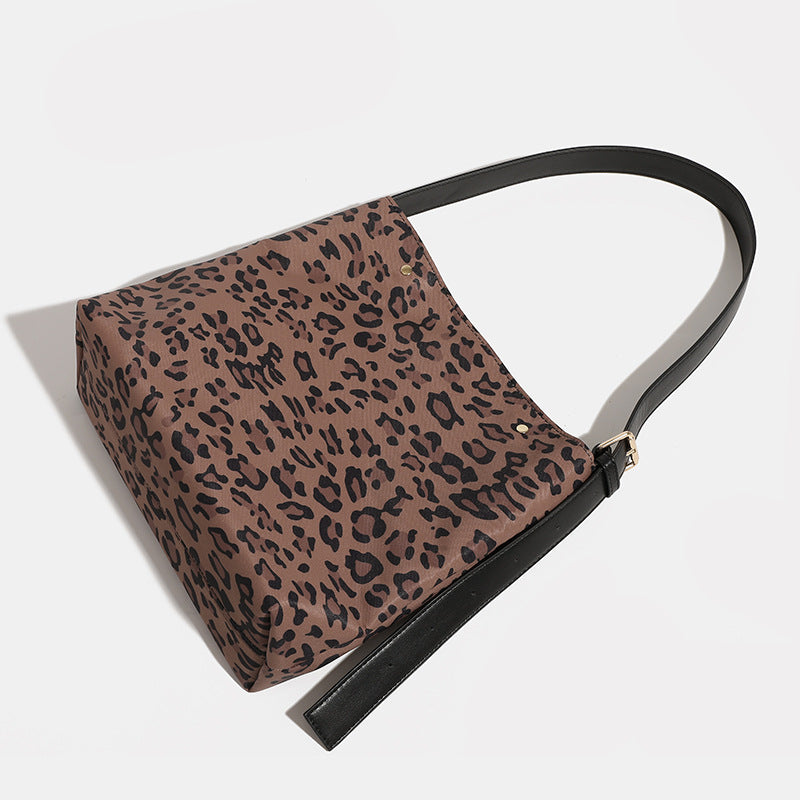 Brown and black leopard print canvas bucket bag with adjustable black leather-look shoulder strap and gold-tone hardware