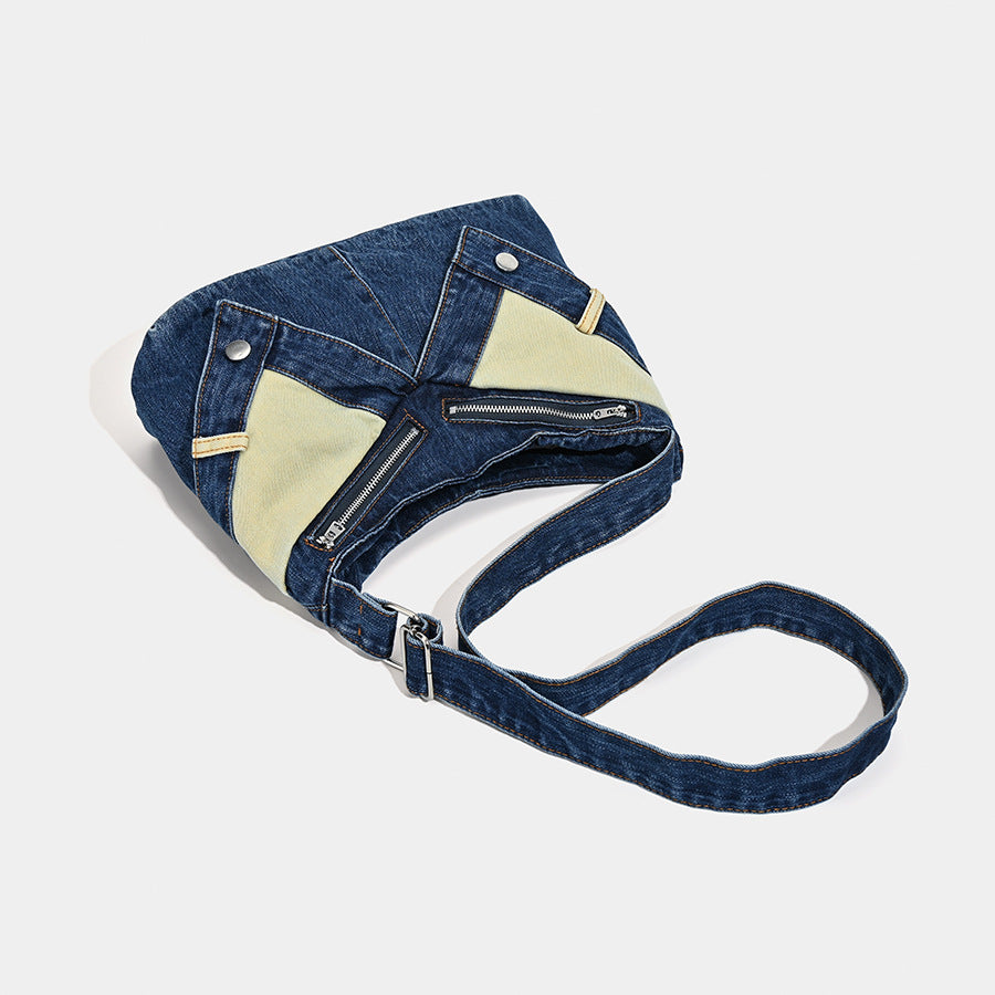 Schultertasche aus indigoblauem Denim mit hellen Kontrastpartien, sichtbarem Reißverschluss in Silberoptik, Druckknopfdetails und langem verstellbarem