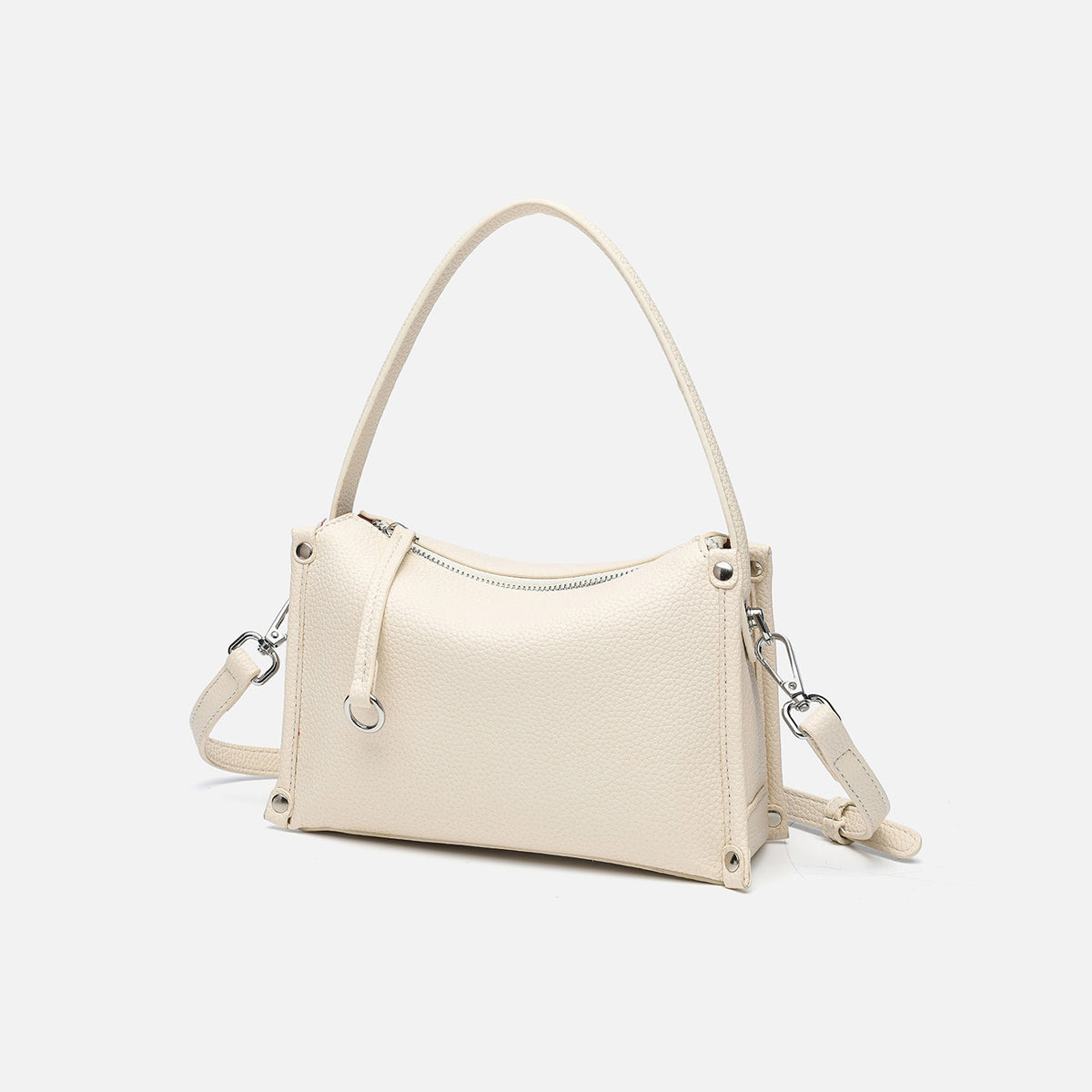 Small structured pebbled-finish convertible bag with silver corner studs, zip top, and detachable shoulder strap, detail view