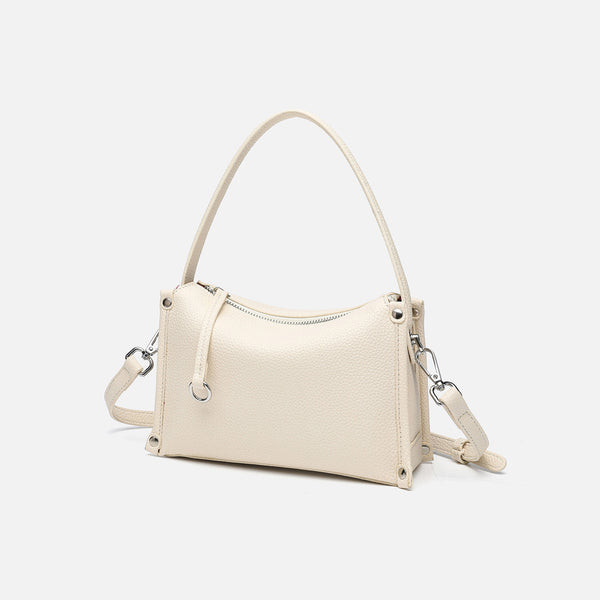 Small structured pebbled-finish convertible bag with silver corner studs, zip top, and detachable shoulder strap, detail view