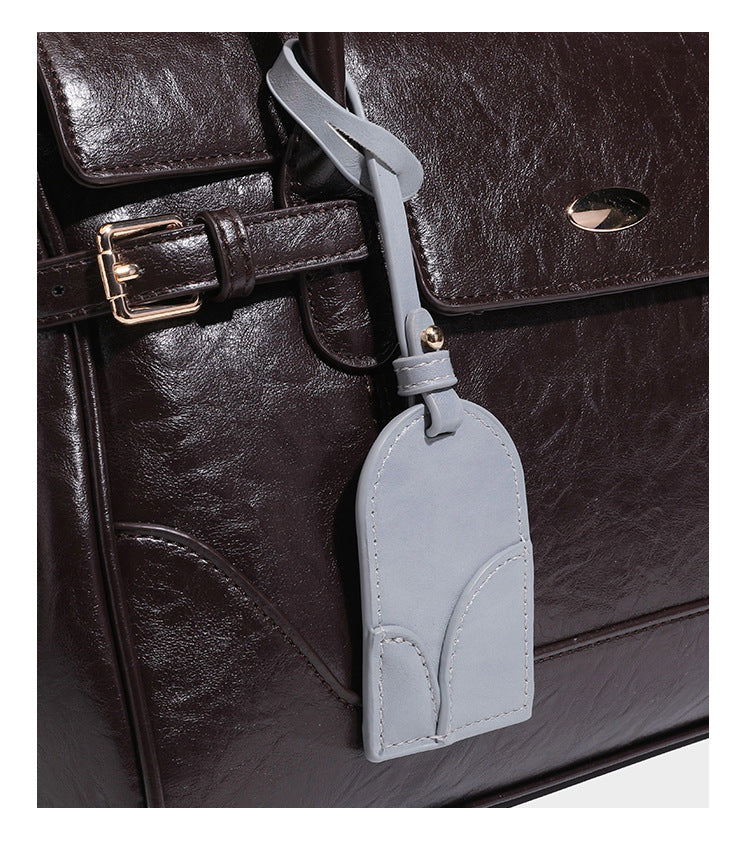 Structured glossy leather-look satchel bag with flap closure, gold-tone buckle accents, double top handles, detachable