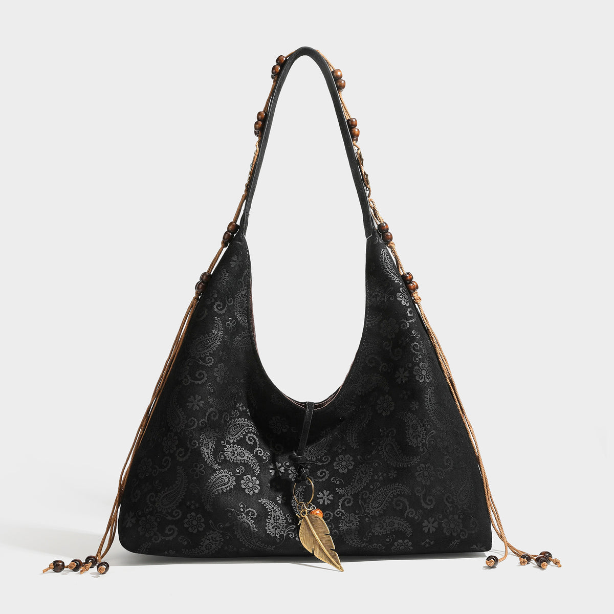 Slouchy boho hobo shoulder bag in embossed brown suede-look finish with beaded strap, cord tassels, and brass-tone leaf