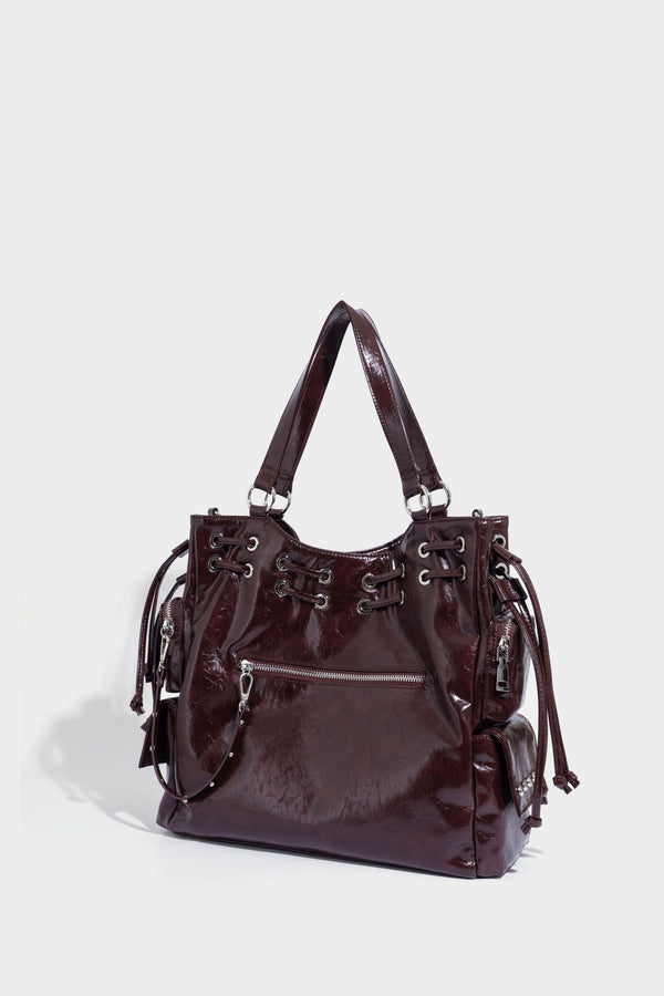 Glossy crinkled leather-look tote bag with silver grommet lace-up front detail, dual top handles, and detachable shoulder