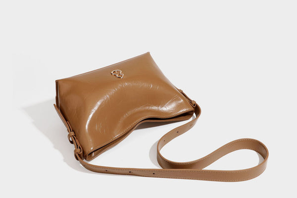 Lässig fallende Hobo-Schultertasche mit offenem Oberteil aus glänzender, karamellbrauner Lederoptik, mit Logo-Beschlägen in Goldoptik und langem, verstellbarem