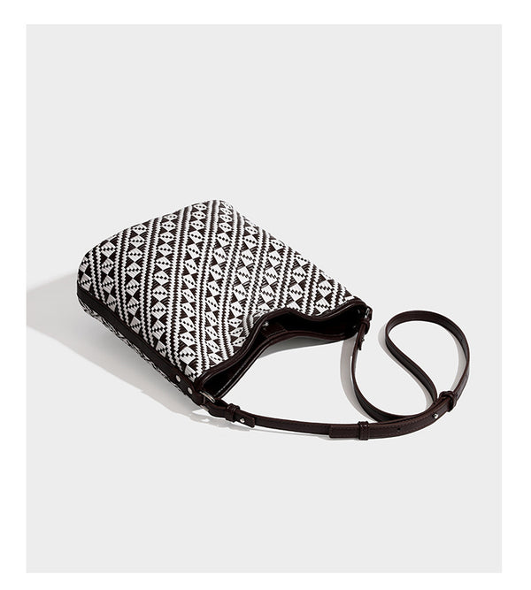 Geflochtene Schultertasche mit geometrischem Ethno-Muster, Besatz in dunkelbrauner Lederoptik, langem verstellbarem Träger und kleinem hängendem Reißverschluss