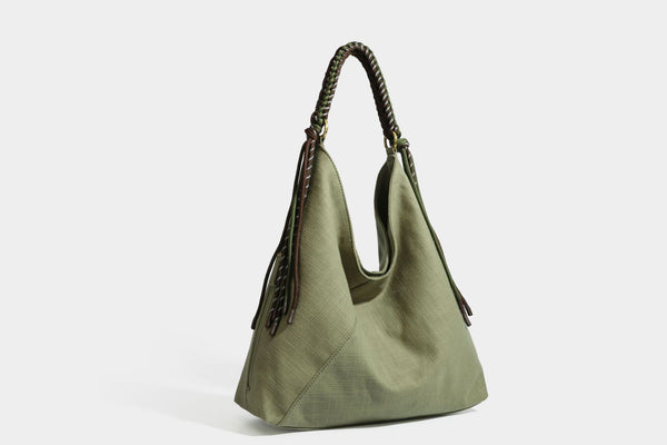 Soft slouchy cream canvas shoulder tote with braided brown and green cord handle, gold-tone ring hardware, and tassel trim