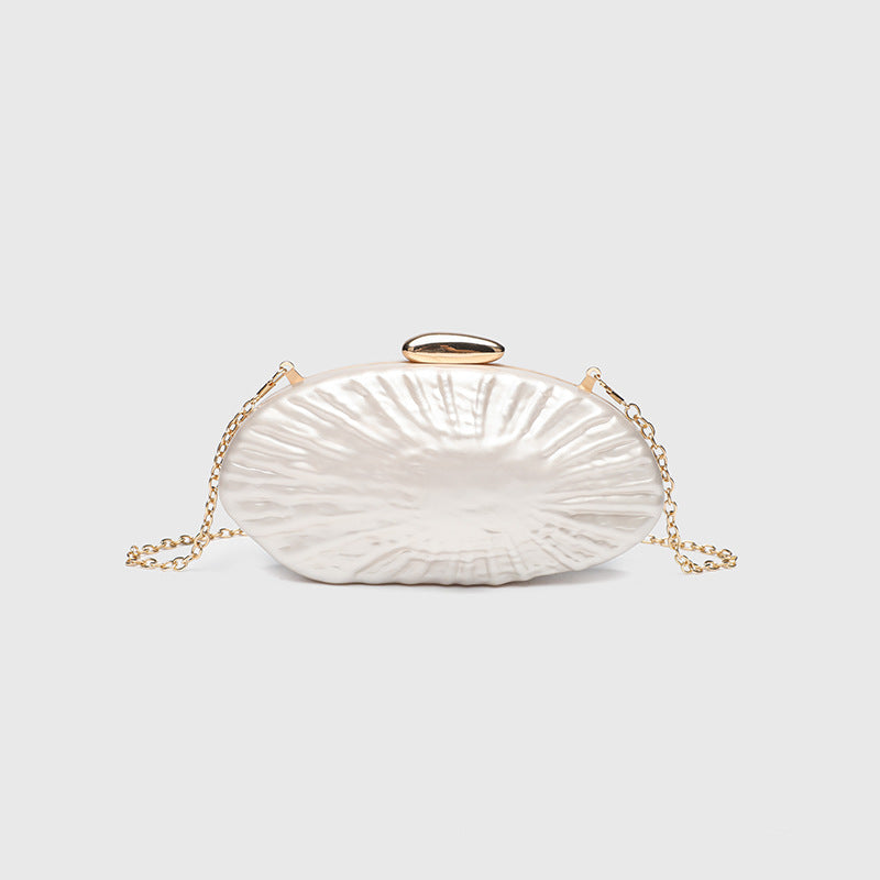 Oval pearl-finish shell clutch bag with gold-tone clasp and removable gold link chain strap, detail view 7