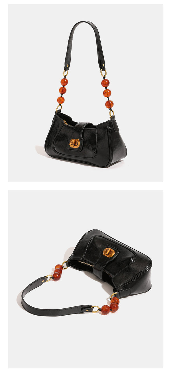 Compact glossy crinkled baguette shoulder bag with amber resin bead strap accent and gold-tone turn-lock closure, detail view