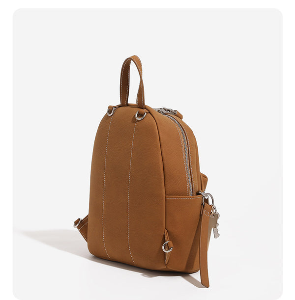 Small rounded mini backpack handbag in pebbled leather-look finish with front zip pocket, silver-tone hardware, and, detail