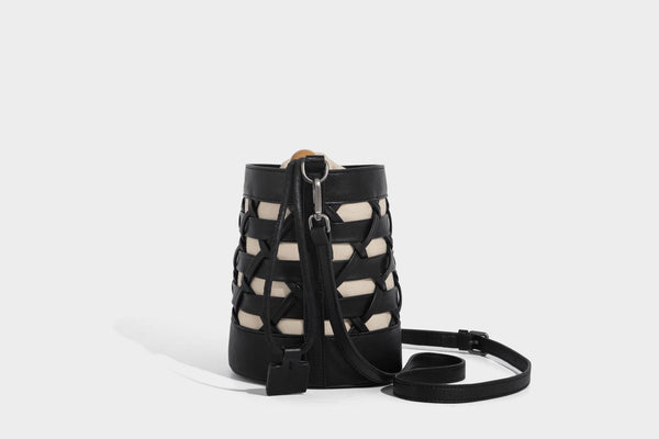 Small cylindrical woven lattice bucket bag with leather-look black trim, beige canvas body, wooden bead drawstring closure