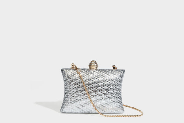 Small structured rectangular metallic woven-texture clutch bag with jeweled knob clasp and gold-tone chain strap, detail view