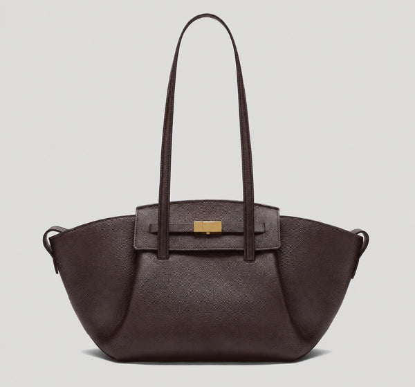 Black pebbled trapezoid tote bag with gold turn-lock hardware and double top handles, detail view 8