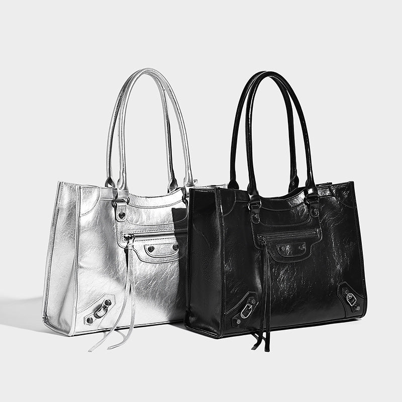 Large structured leather-look tote bag with front zip pocket, moto hardware accents, and long double shoulder straps, detail