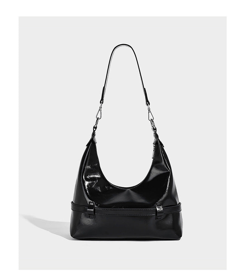 Glossy black slouchy hobo shoulder bag with silver-tone hardware, belt-style grommet strap at base, and long adjustable