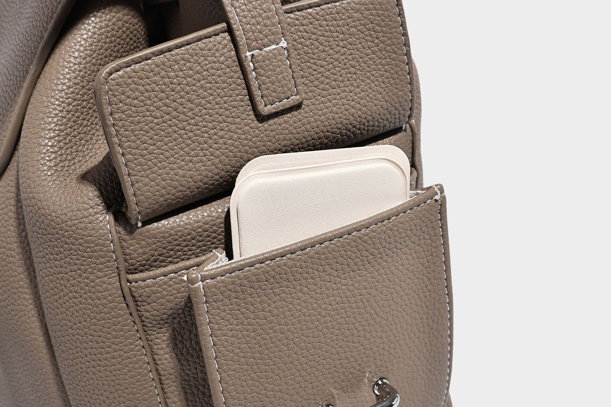 Compact pebbled leather-look flap drawstring backpack handbag with side pockets, top handle, and silver-tone hardware, detail
