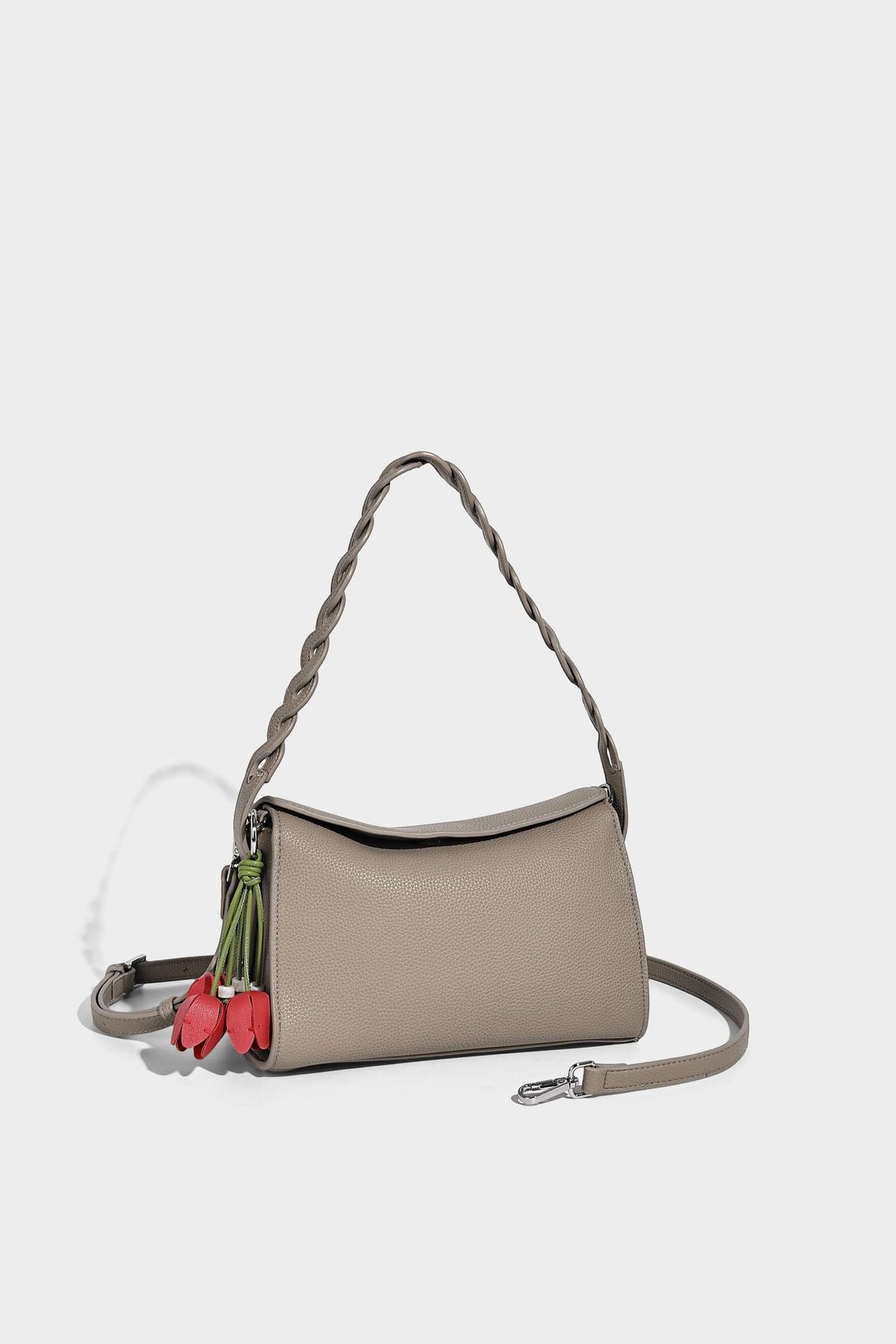 Small structured pebbled-finish shoulder bag with braided top handle, detachable crossbody strap, floral tassel charm, and