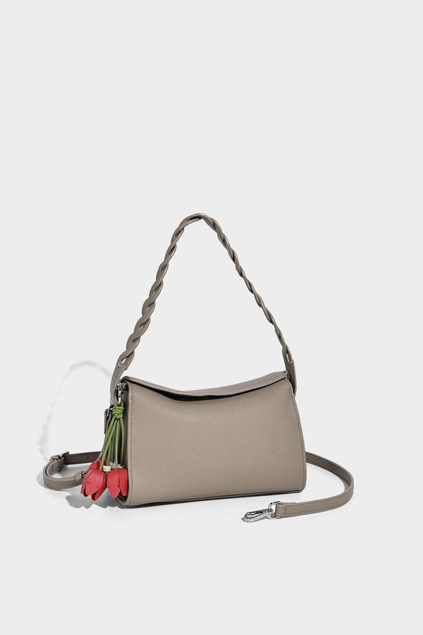 Small structured pebbled-finish shoulder bag with braided top handle, detachable crossbody strap, floral tassel charm, and