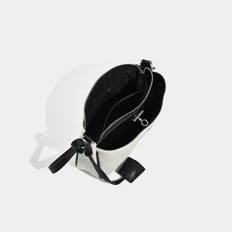 Small structured cream crossbody bag with contrast leather-look trim, silver-tone turn-lock hardware, and adjustable