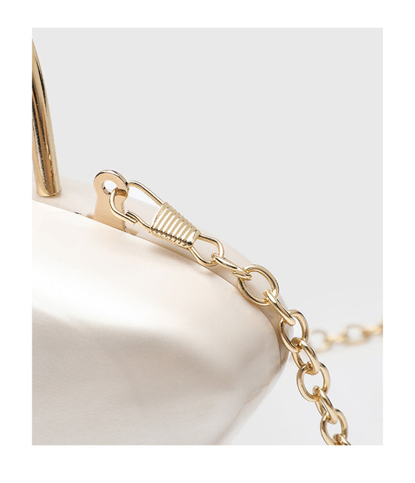 Shell-shaped pearlescent top-handle clutch bag with arched gold-tone metal handle and gold chain strap, detail view 17