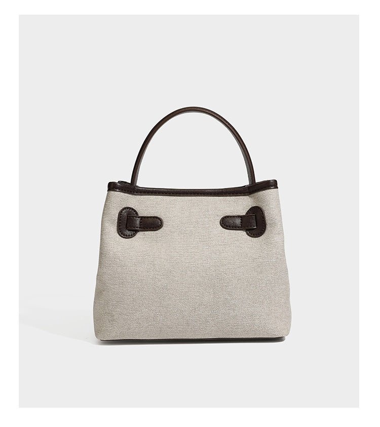 Small structured beige canvas top-handle bag with dark brown leather-look trim, silver turn-lock hardware, and detachable