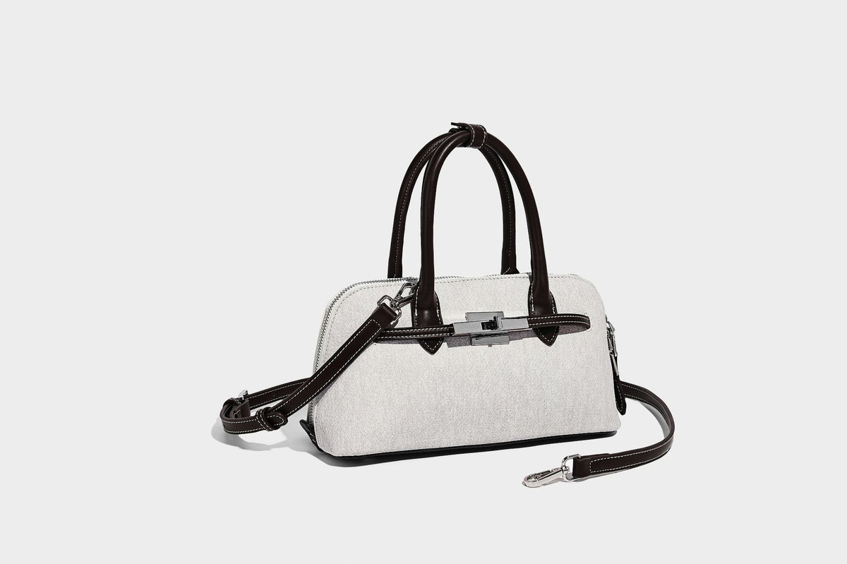 Compact structured satchel in light blue denim-look fabric with black leather-look trim, silver turn-lock closure, rolled