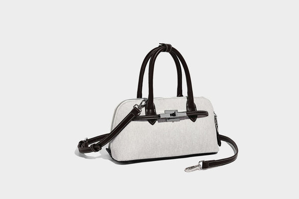 Compact structured satchel in light blue denim-look fabric with black leather-look trim, silver turn-lock closure, rolled
