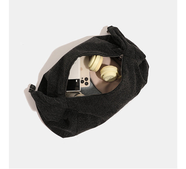 Oversized slouchy black textured canvas hobo shoulder bag with zip-top closure and adjustable dark-hardware strap, detail