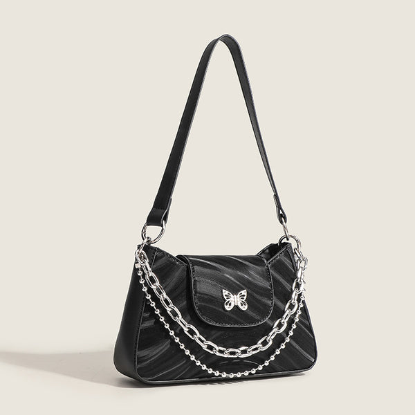 Small trapezoid shoulder bag with ripple leather-look finish, silver butterfly front clasp, and layered chain-and-ball strap