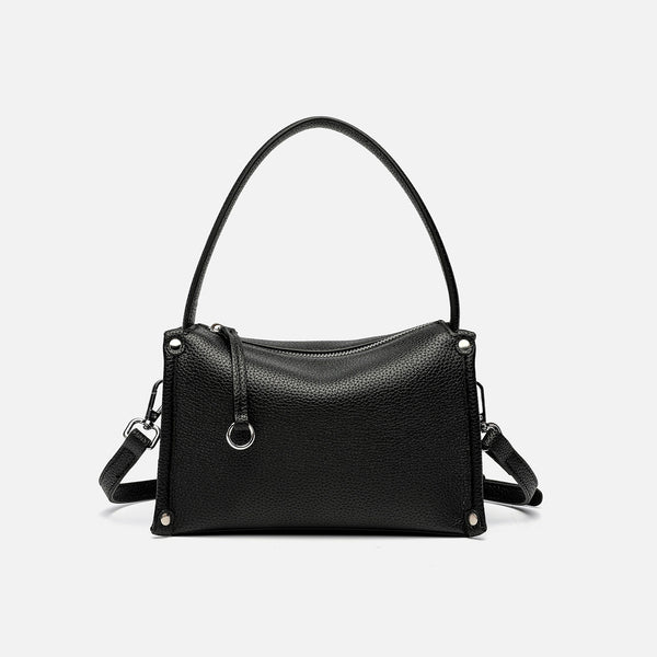 Small structured pebbled-finish convertible bag with silver corner studs, zip top, and detachable shoulder strap, detail view