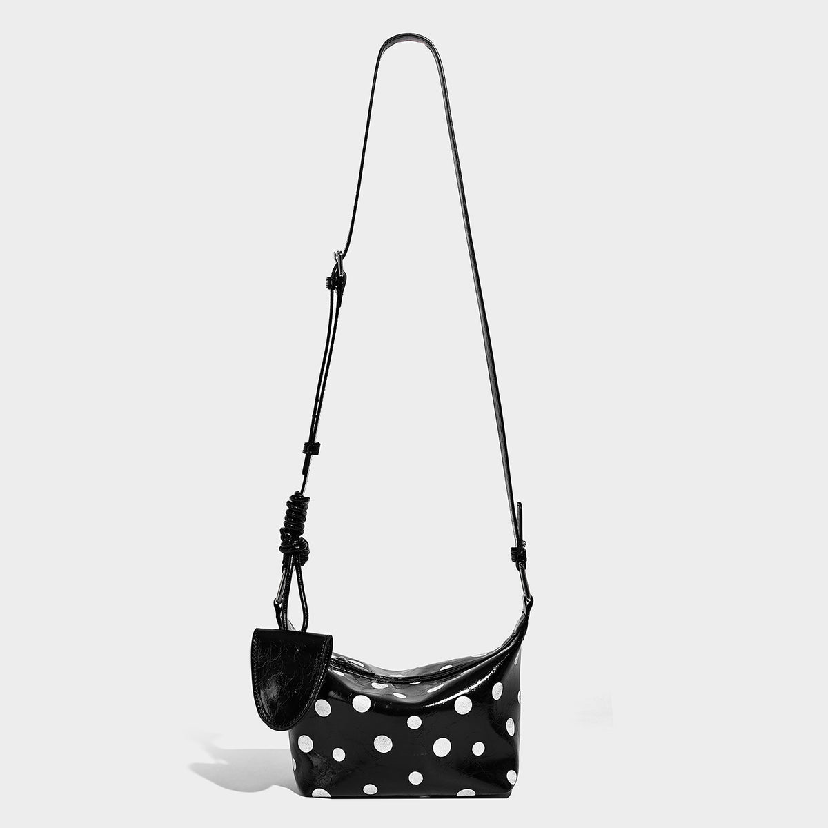Kompakte glänzende Hobo-Schultertasche in Schwarz mit weißen Punkten, Reißverschluss, gunmetallfarbenen Beschlägen und fest angebrachter Frontklappe