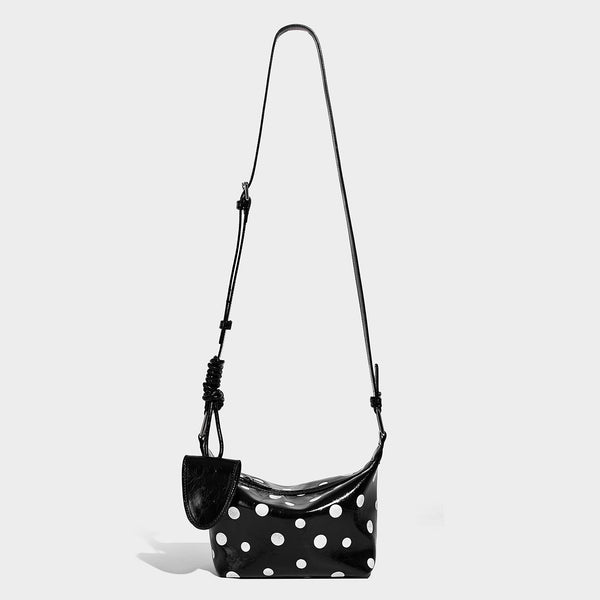 Kompakte glänzende Hobo-Schultertasche in Schwarz mit weißen Punkten, Reißverschluss, gunmetallfarbenen Beschlägen und fest angebrachter Frontklappe
