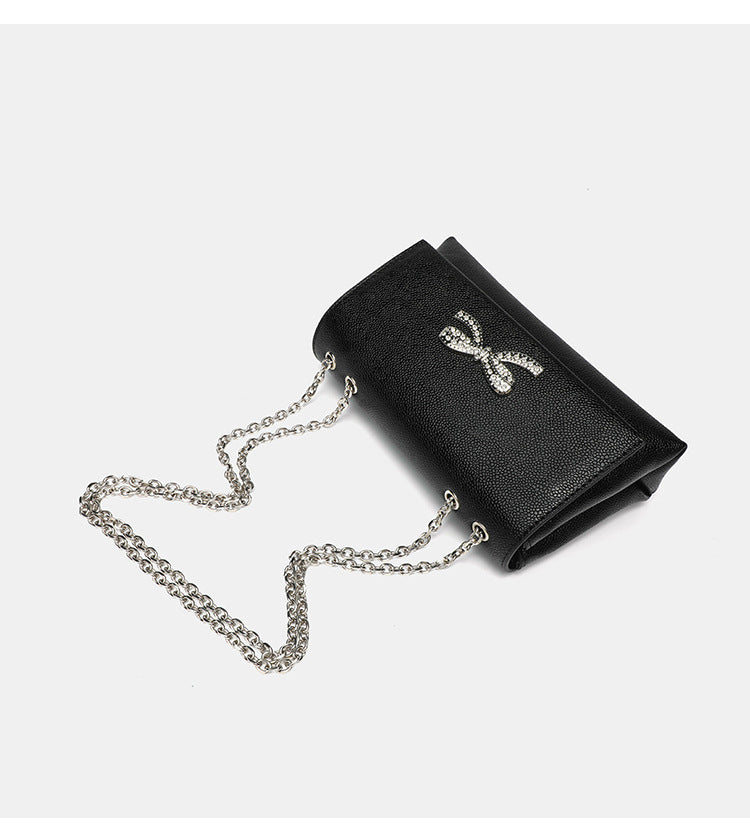 Structured rectangular flap crossbody bag with rhinestone bow and silver chain strap in pebbled finish, detail view 10